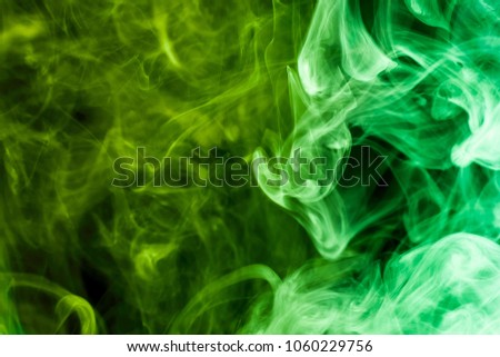 Dense multicolored smoke of  green and yellow colors on a black isolated background. Background of smoke vape