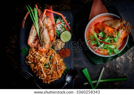 Concept pictures of famouse Thai dishes, Tom Yum Kung & Phad Thai. Beautiful presentation on black stone and black background.