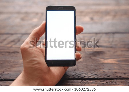 mens hand holding smartphone with blank screen for your logo or design on dark wooden table