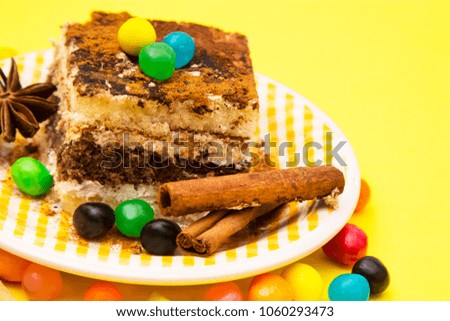 delicious portion of tiramisu with candies and cinnamon on yellow background