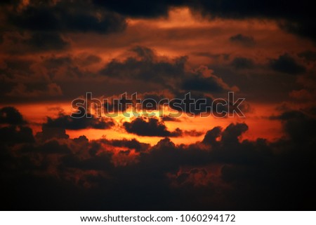 Warm Orange Red Sunset Sky and Clouds Pattern Pictures. Flaming sunset with light passing through dark clouds. Landscape.