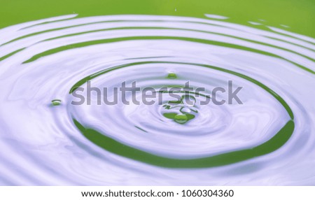 Close up of splashing droplet and water surface. Abstract background.