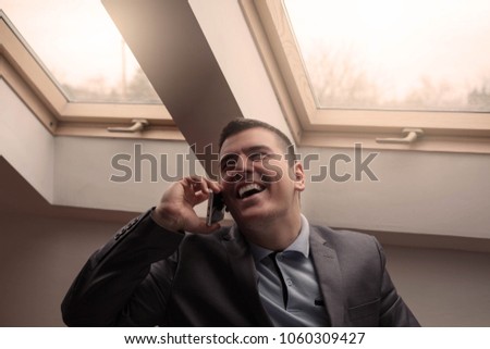 Happy businessman smiling and using cell phone.