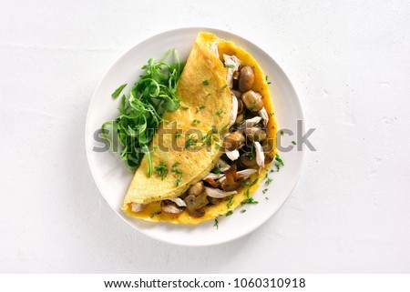 Omelette stuffed with mushrooms, pieces of chicken meat, greens on white stone background. Top view, flat lay Royalty-Free Stock Photo #1060310918