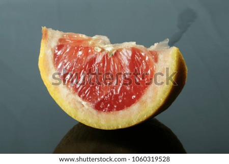 Close up of pink grapefruit slice on dark background.