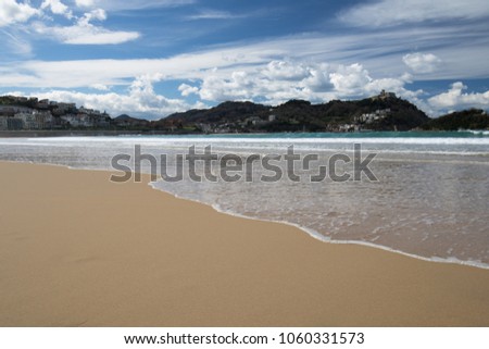 beautiful sandy beach with view on monte igueldo and santa clara island in san sebastian, spain