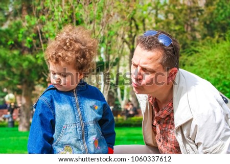 Little boy is fussing on the street. The father tries to calm, comfort and cheer the young child. The father and the son.