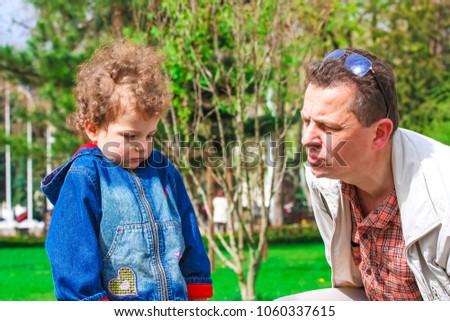 Little boy is fussing on the street. The father tries to calm, comfort and cheer the young child. The father and the son.