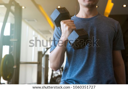 Young man beginner exercising with dumbbell flexing muscles at gym, sport training concept Royalty-Free Stock Photo #1060351727