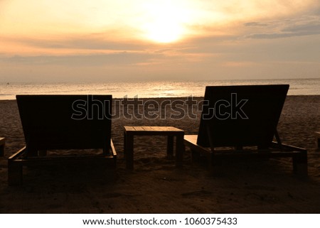 The golden morning sun, orange, and wooden beds serve tourists at one beach.