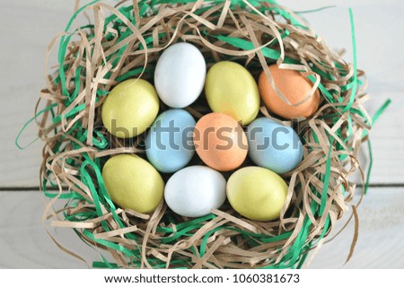 A nest of strips of paper, imitating a bird's nest. In the nest lie candy in the form of eggs. Light background. View from above. Close-up. Macro photography.