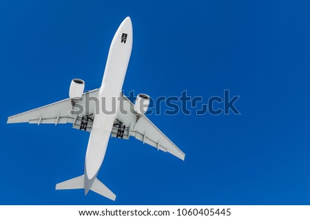 long haul widebody white passenger airplane on a blue sky background. bottom view a few seconds before landing. composition photography. flying overhead towards destination airport. travel concept.