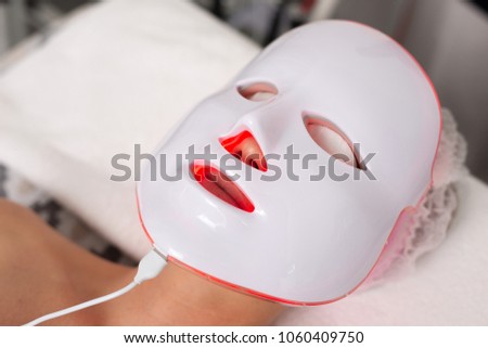 A red LED face masque on a caucasian lady in a spa. Royalty-Free Stock Photo #1060409750