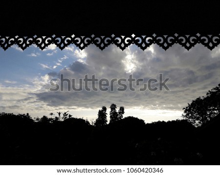 Silhouette of trees line with eaves of thai house and a cloudy day