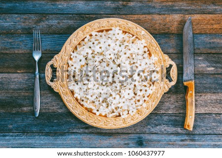 spring abstraction. fruit tree flowers in Golden dish, fork and knife on old wooden table, top view closeup