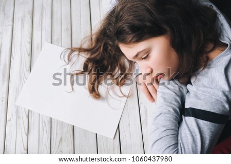 A girl with a clean sheet of paper. The crisis of inspiration concept.