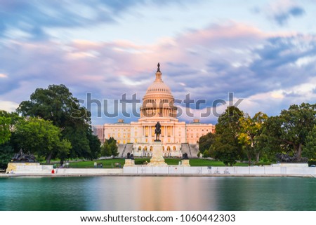 The United States Capitol building at sunset wirh reflection in water.