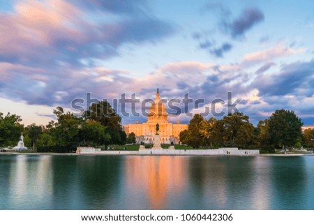 The United States Capitol building at sunset wirh reflection in water.