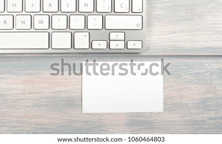 Business card in white color next to computer keyboard. Mockup.
