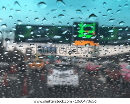 Blurred background, water drops on the windshield, traffic in the city on a rainy day, car windshield view, colorful bokeh.