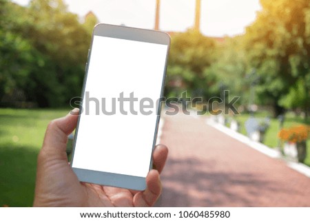 Selfie photo concept : Mock up Extensible selfie stick or monopod with mobile phone taking picture shot at green trees view outdoor background.