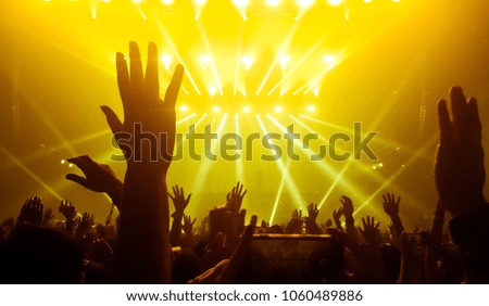 Happy people dance in nightclub party concert and listen to music from DJ on the stage in background. Cheerful crowd celebrate Christmas and New Year party 2018. Young people lifestyle and nightlife.