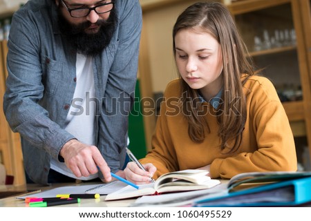 Young teacher helping his student in chemistry class. Education, Tutoring and Encouragement concept.  Royalty-Free Stock Photo #1060495529