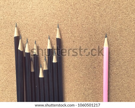 Pink pencil standing out from crowd of plenty identical black on board background , differences, leadership, uniqueness, initiative, strategy, dissent, think different, business success concept