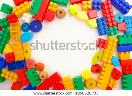 Toys background. Colorful wooden cubes and plastic construction blocks frame on white background.