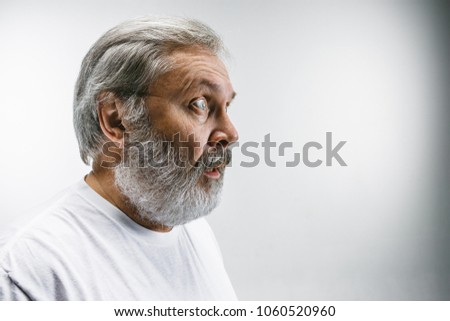 Wow. Attractive male half-length front portrait on white studio backgroud. Senior emotional surprised bearded man with open mouth. Human emotions, facial expression concept. Profile
