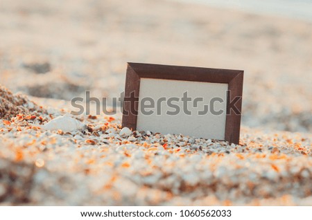 Photo frame on sand background, sea at sunset place for lettering, copyspace