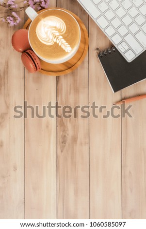 Flat lay top view office table desk. Workspace with blank note book, keyboard, macaroon, flowers and coffee cup on wooden background.