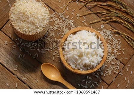 Jasmine rice in wood bowl and paddy rice on a brown wooden background beautiful Thai food Royalty-Free Stock Photo #1060591487