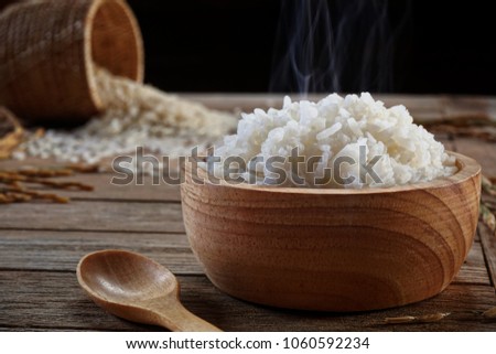 Jasmine rice in wood bowl and paddy rice on a brown wooden background beautiful Thai food Royalty-Free Stock Photo #1060592234