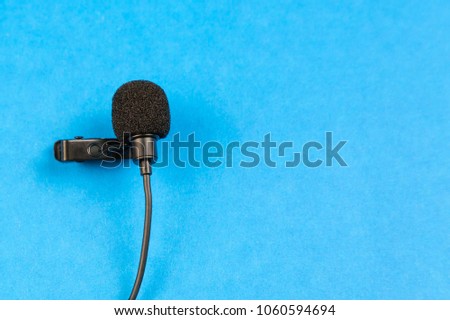 Miniature microphone of the buttonhole. A small microphone for recording quality sound on a blue background. Lavalier microphone