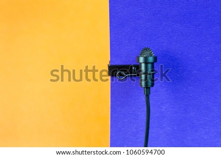 Miniature microphone of the buttonhole. A small microphone for recording quality sound on a blue background. Lavalier microphone