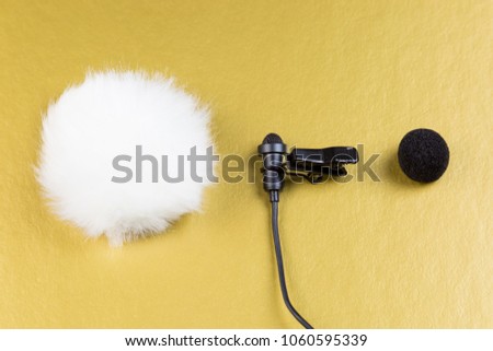 Miniature microphone of the buttonhole. A small microphone for recording quality sound on a gold background. Lavalier microphone