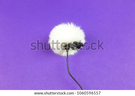 Miniature microphone of the buttonhole. A small microphone for recording high-quality sound on a purple background. Lavalier microphone