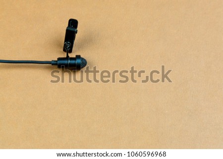 Miniature microphone of the buttonhole. A small microphone for recording quality sound on a brown background. Lavalier microphone