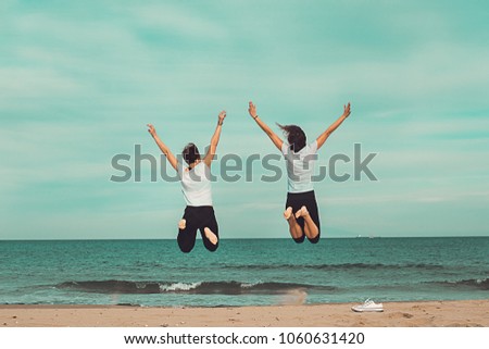 Two people jumping by the sea. Concept of fun on the beach. Jumping and with arms raised