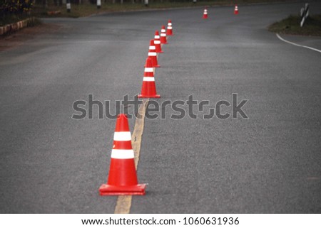 Blurred bright orange traffic cones standing in a row on dark asphalt
