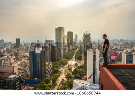 Young men standing on the rooftop building in Mexico city. Paseo de la Reforma panoramic view. Extreme men on the rooftop