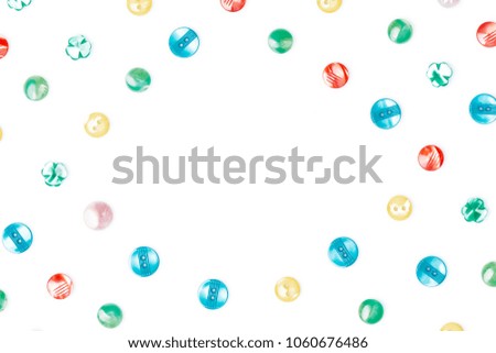 Colorful sewing buttons on a blank (white) background, arranged on corners, with a copy space in the center. Top view.