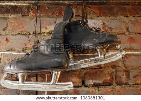 Old black hockey skates hanging on the brick wall
