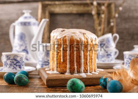 A table served for Easter. Fresh Russian cake and dyed quail eggs on a wooden background. With an ancient frame in the background.