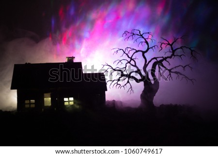 Old house with a Ghost at night with spooky tree or Abandoned Haunted Horror House in toned foggy sky with light. Old mystic building in dead tree forest. Horror Halloween concept.