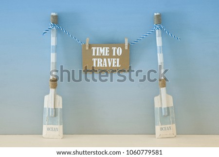 nautical concept with wooden decorative boat oars and note hanging on a string over blue background