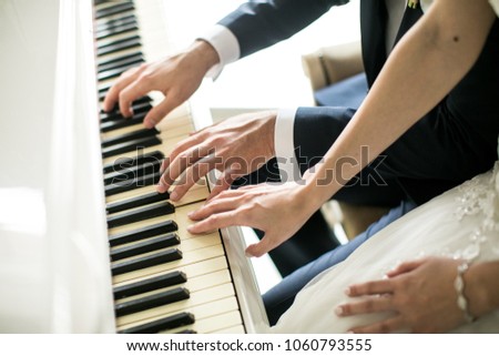 man with a woman playing on a white piano