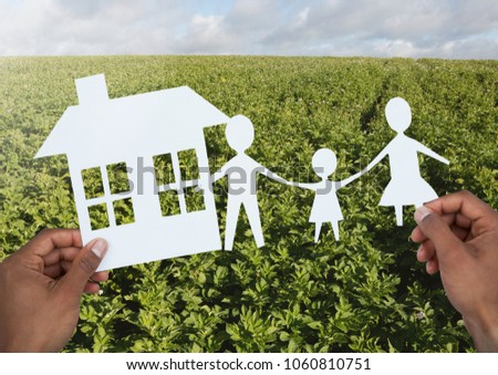 Cut outs house and family in hands over landscape