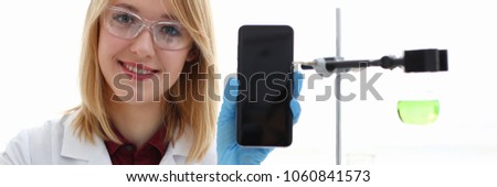 A female doctor in a chemical laboratory holds a smartphone in his hand with display, you can insert a picture or an image you want to write for an advertising company